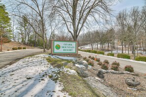 Schild für das Ozark Mountain Resort mit Blick auf eine verschneite Landschaft und Bäume.