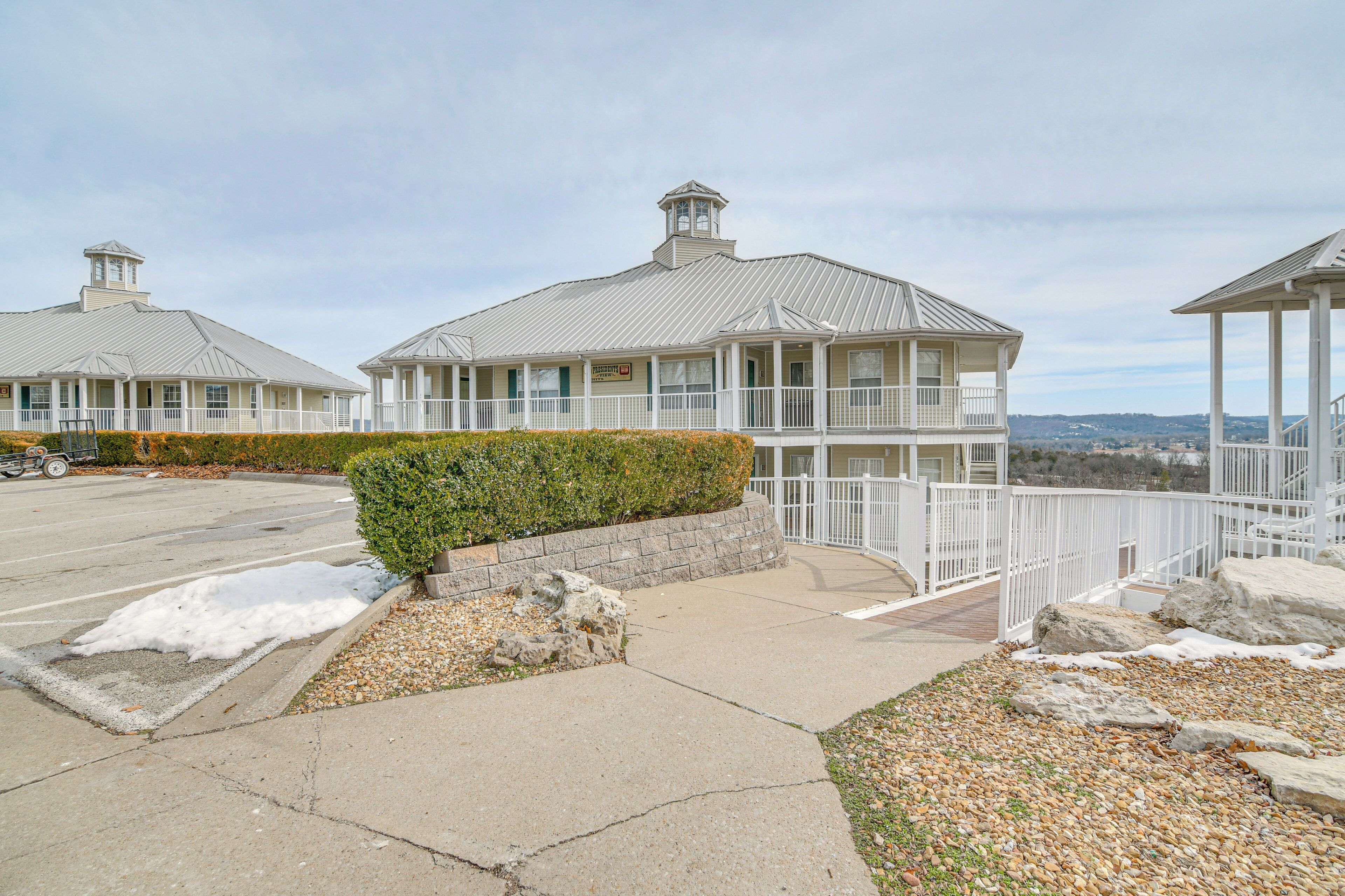 A coastal building with a balcony, a stone retaining wall, and a view of the ocean.
