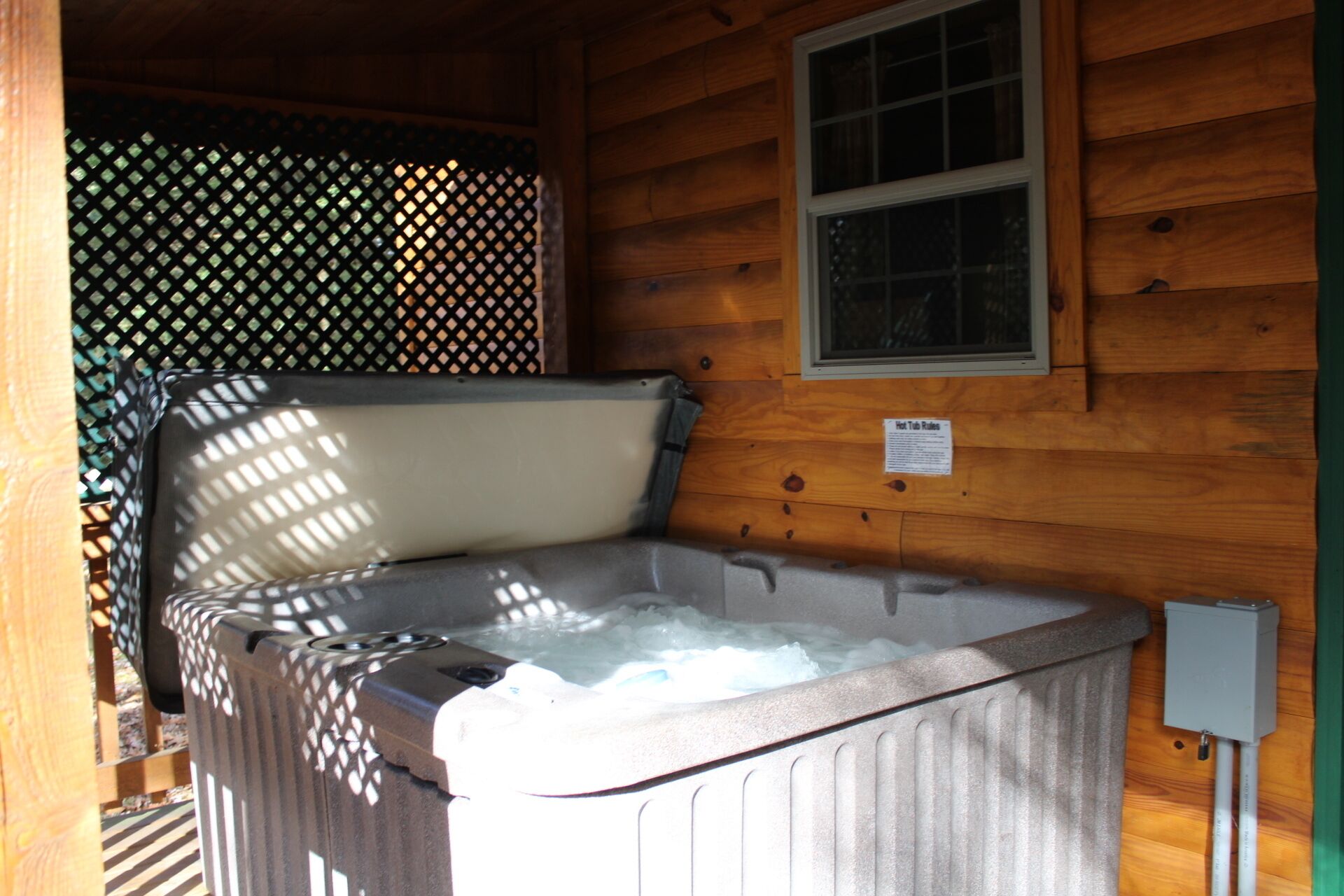 Een hottub in een houten hut met een raam erboven.