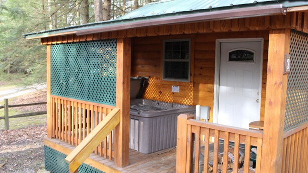 Una cabaña de madera con un porche, un jacuzzi y una puerta con un letrero de número.