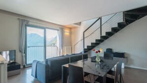 Una sala de estar moderna con un sofá, una mesa de comedor y sillas. Una escalera conduce a un nivel superior.
