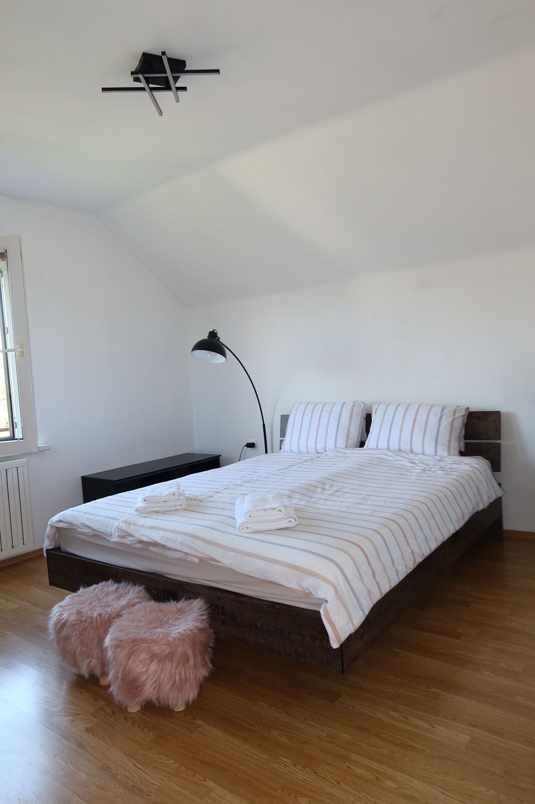 A bedroom with a bed, a bedside table, a lamp, and a fluffy rug.
