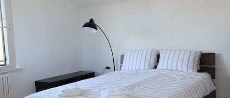 A bedroom with a bed, a bedside table, a lamp, and a fluffy rug.