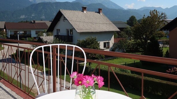 Et rundt bord med en blomstervase på en balkon med udsigt til et bjerglandskab.