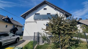 Et moderne hus med to etager, hvid facade, skråtag og en balkon.