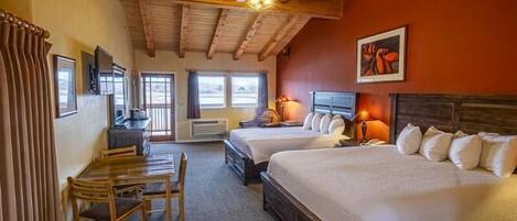 A hotel room with two beds, a desk, a chair, and a ceiling fan.