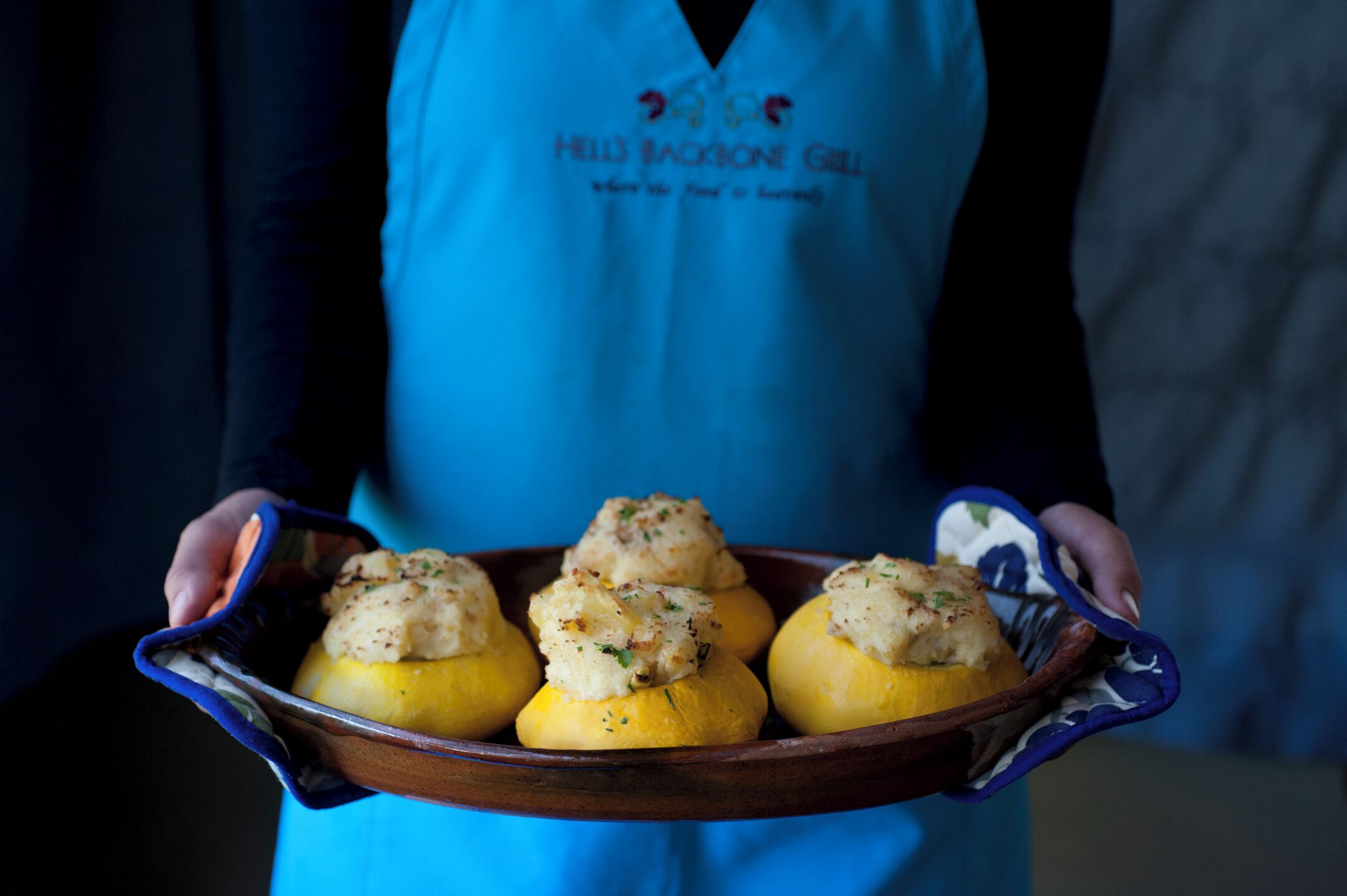 A person holding a tray with stuffed squash.