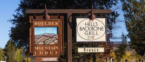 A sign for Boulder Mountain Lodge with a vacancy notice and a sign for Hell's Backbone Grill.