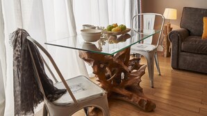 Een eetgedeelte met een glazen tafel, stoelen en een houten decoratie.