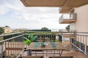 A balcony with a table set for two, overlooking a cityscape and the sea. - Apartment in Ságaró with sea view and swimming pool (Sant Feliu de Guíxols)