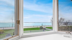 A room with a large window overlooking a body of water and a road.