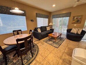 A living room with a round table, two sofas, a coffee table, and a TV.