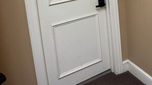 A white door with a black letter 'B' above it, a doorknob, and a small hole in the center. - Lofts on Murphy by Rooms336 (Madison)