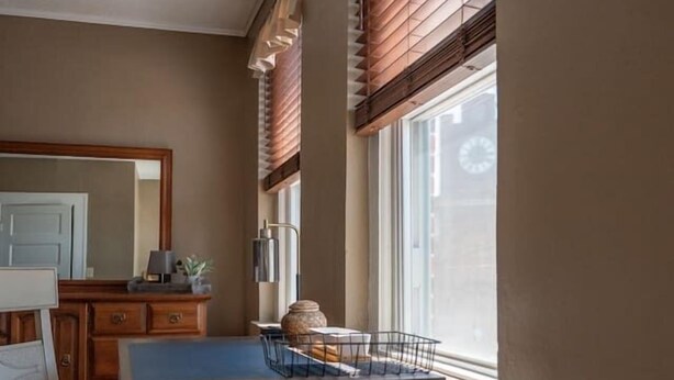 Una habitación pequeña con escritorio, silla y un ventanal con persianas.