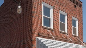 Un edificio de ladrillo de dos pisos con techo plano y un pequeño toldo sobre la entrada.