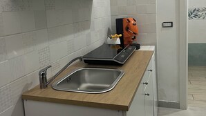 A modern kitchen with white cabinets, a stainless steel sink, and a built-in induction cooktop. - Cottage frm home (Napoli)