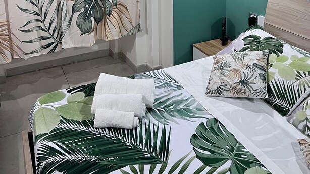 A bedroom with a bed, a nightstand, a wall-mounted light, and a decorative item on the wall. - Cottage frm home (Napoli)