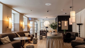A modern hotel lobby with sofas, a round table, and pendant lighting. - Casa Teva Lisboa by chic&basic (Lisbon)