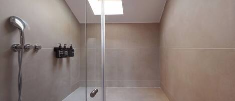A modern shower with a glass door, a skylight, and a control panel.