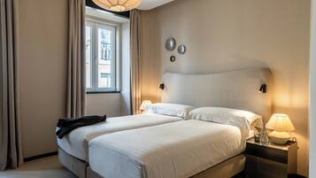 A double bed with a headboard, bedside lamps, and a window with curtains.
