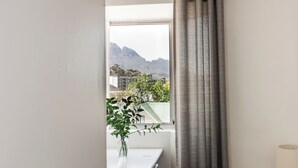 A room with a window, a table with a vase of flowers, and a lamp. - Spacious Central Apartment (Stellenbosch)