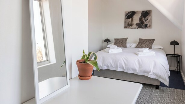 A modern bedroom with a large bed, a potted plant, a bedside table, and a ceiling fan. - Spacious Central Apartment (Stellenbosch)