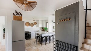 A modern kitchen with a large refrigerator, bar stools, and a hanging light fixture. - Spacious Central Apartment (Stellenbosch)