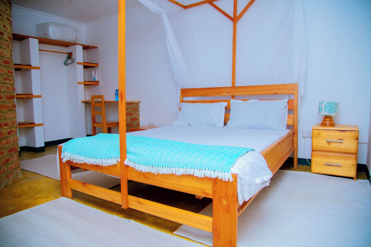 Une chambre à coucher avec un lit à baldaquin, une table de chevet en bois, un mur en briques et un plafond blanc.