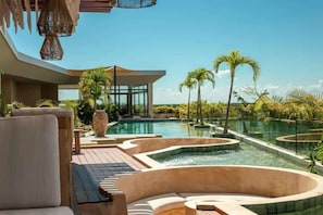 A modern pool area with lounge chairs, a hot tub, and a clear view of the surrounding landscape.