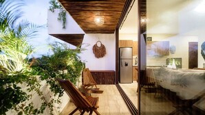 A modern interior with a dining area, wooden chairs, a sofa, and a kitchen with a refrigerator. - Nasha Tropical Bliss Plunge Pool Beach Club Access (Tulum)