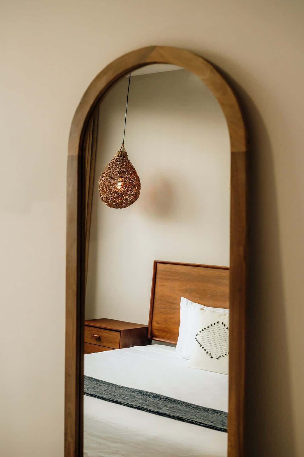 A bedroom with a wooden headboard, a bedside table, and a hanging light fixture.