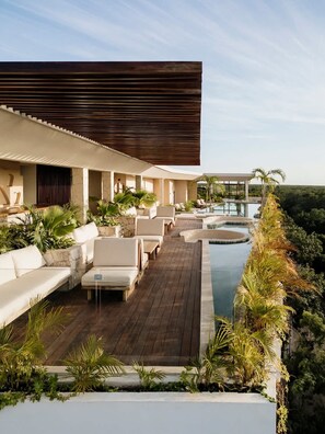 A modern outdoor lounge area with a pool, seating, and a view of the landscape. - Nasha Tropical Bliss Plunge Pool Beach Club Access (Tulum)