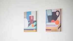 Ein Essbereich mit einem Tisch für vier Personen, zwei abstrakte Gemälde an der Wand und einem grünen Stuhl.