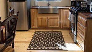 Eine Küche mit Holzschränken, einem Edelstahlkühlschrank, einem Gasherd und einer Mikrowelle.