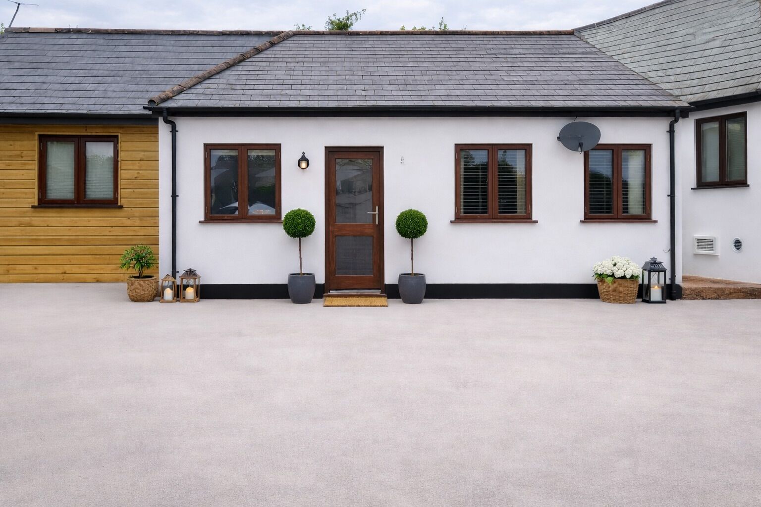 Une maison à deux étages avec une porte d’entrée, deux fenêtres au rez-de-chaussée et une antenne parabolique sur le toit.