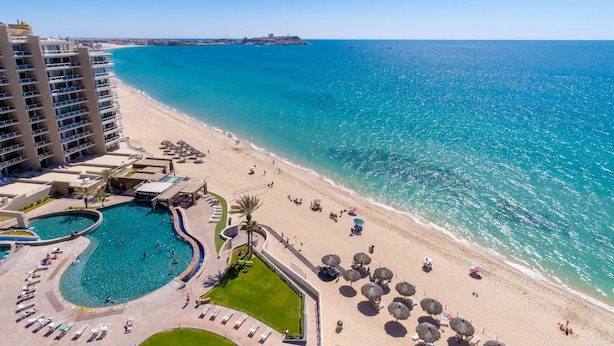 Een resort met een groot zwembad, strand en uitzicht op de oceaan.