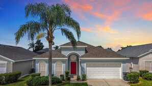 A residential house with a garage, a red door, and a well-maintained lawn. - -NEW LISTING- Disney home w/ Pool, Hot Tub & 2 King En-Suites- 4 miles to Disney (Kissimmee)