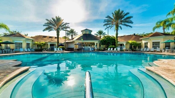 A swimming pool with lounge chairs and palm trees. - -NEW LISTING- Disney home w/ Pool, Hot Tub & 2 King En-Suites- 4 miles to Disney (Kissimmee)