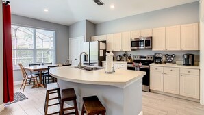 A modern kitchen with a central island, stainless steel appliances, and light-colored cabinetry. - -NEW LISTING- Disney home w/ Pool, Hot Tub & 2 King En-Suites- 4 miles to Disney (Kissimmee)