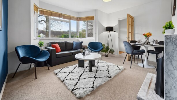 Een moderne woonkamer met een bank, stoelen, een salontafel en een eethoek met een tafel en stoelen.