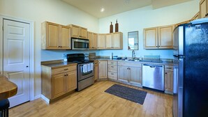 A modern kitchen with wooden cabinets, stainless steel appliances, and a black refrigerator. - Blue Moon Retreat ~~ Spacious duplex unit with SAUNA and a stunning view (Joseph)