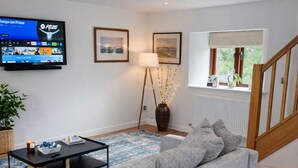 A living room with a grey sofa, a coffee table, a TV, and a lamp.
