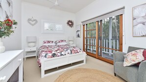 Quarto com cama, escrivaninha, cadeira, janela e ventoinha no teto.