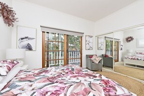 Een slaapkamer met een bed, een stoel, een grote spiegel en kunstwerken aan de wanden.