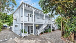 A two-story house with a balcony and a staircase leading to a porch. - The Palms Retreat - Top Floor Apartment style (Nelson Bay)