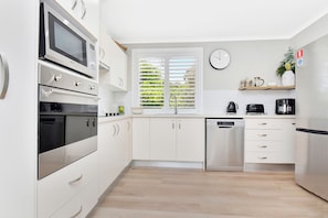 Een moderne keuken met witte kasten, roestvrijstalen apparatuur, een inbouwoven en een vaatwasser.