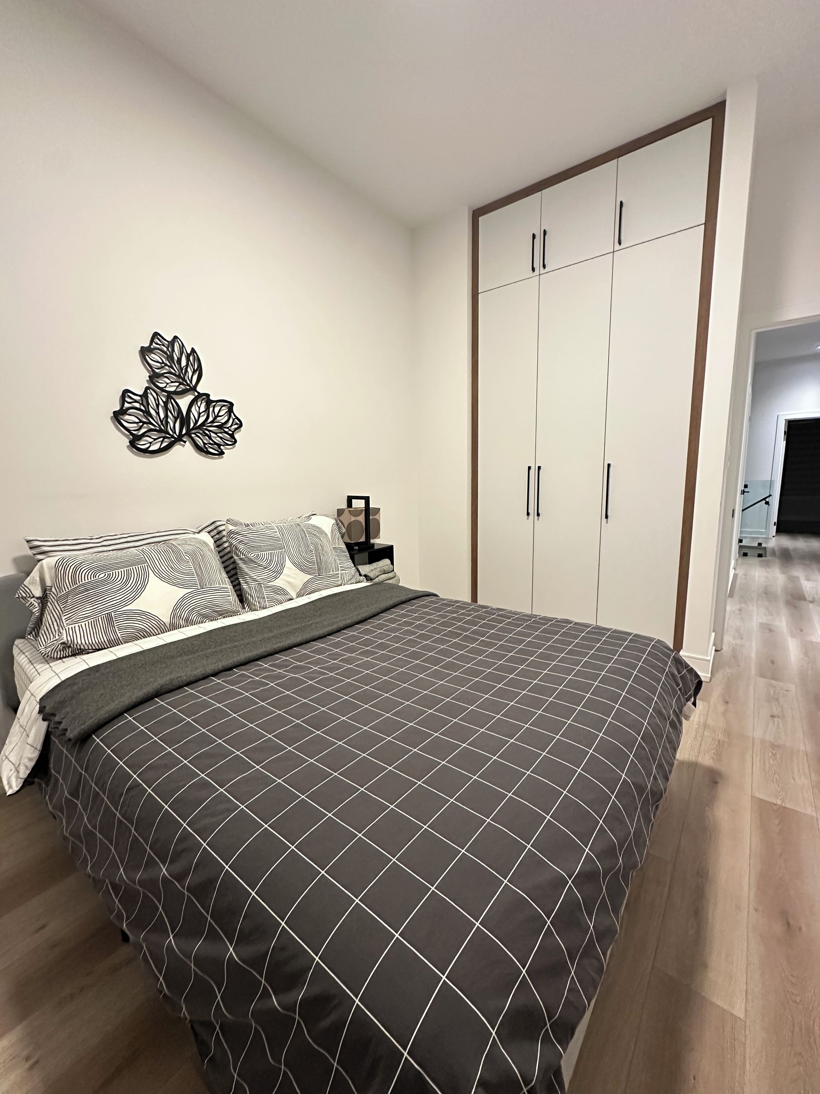 Ein Schlafzimmer mit Bett, Nachttisch, Wandbild und Kleiderschrank.