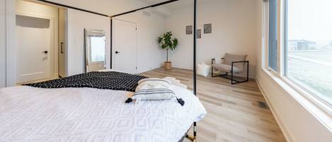Une chambre à coucher moderne avec un lit, une fenêtre, une plante et une chaise.