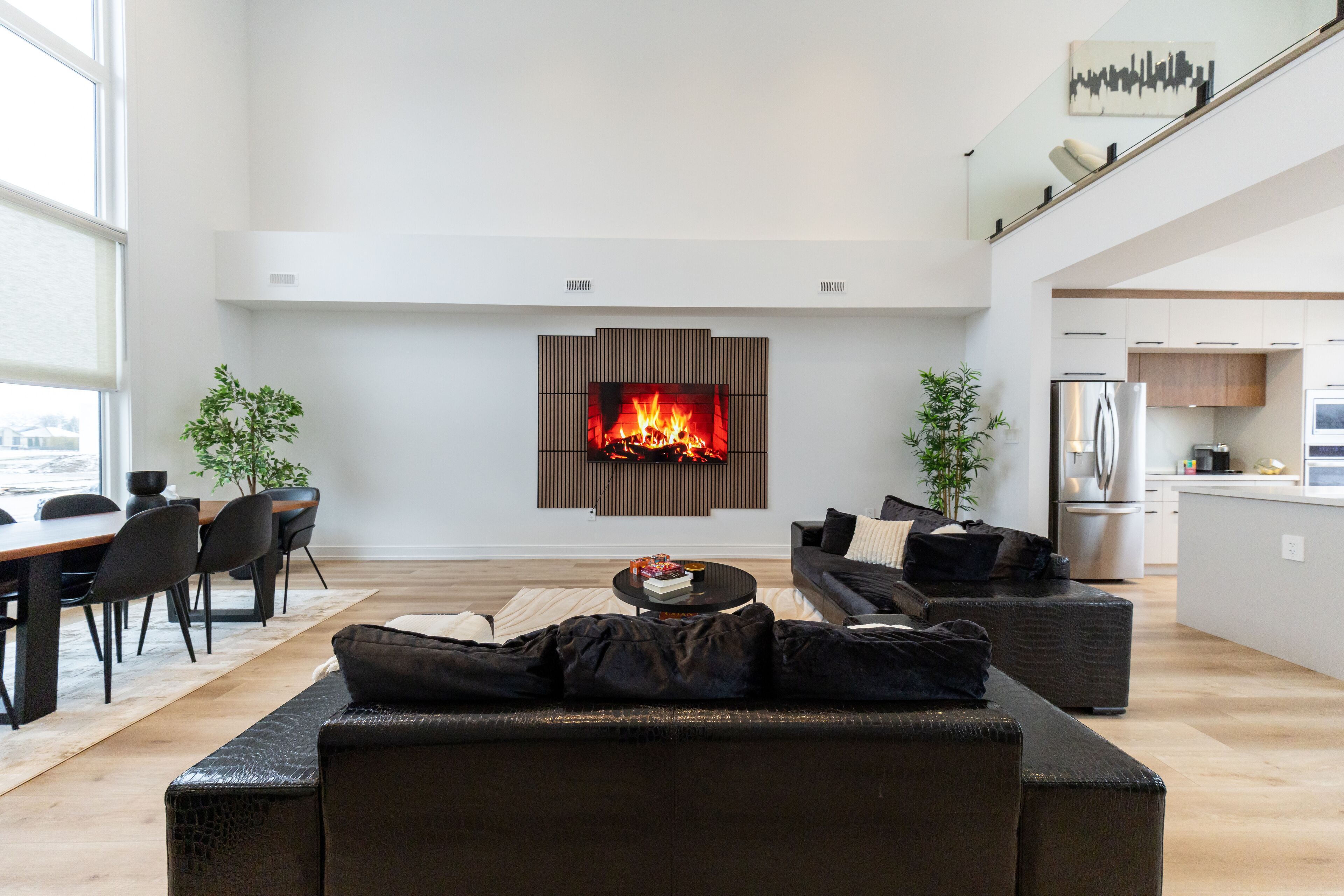 Una sala de estar moderna con chimenea, comedor y cocina.