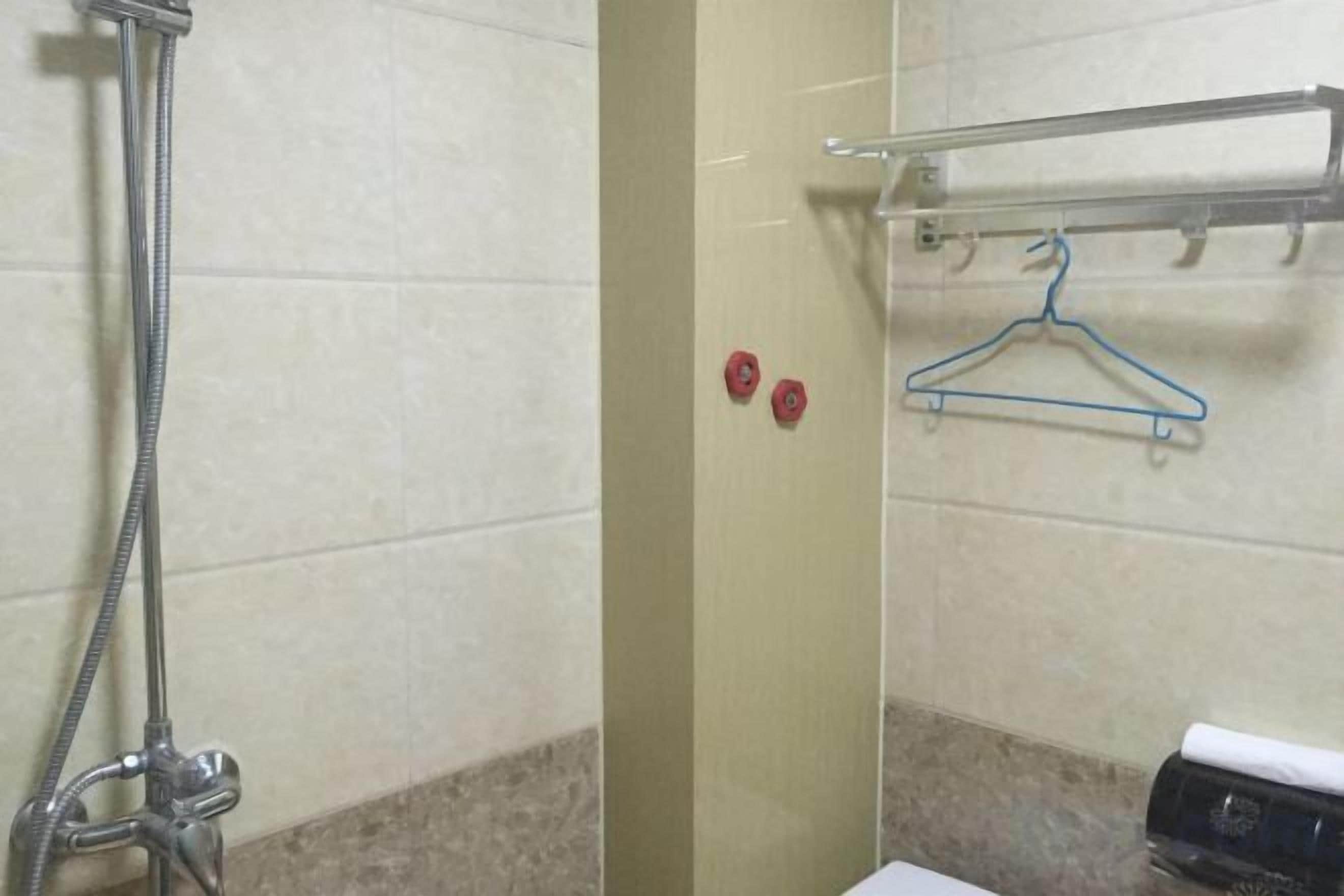 A bathroom with a shower, a towel rack, and a toilet paper dispenser.